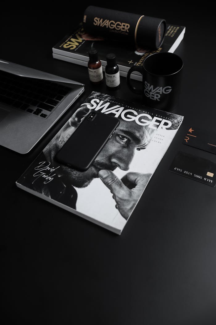 Stylish black desk layout with Swagger magazine, smartphone, and gadgets, showcasing modern lifestyle elegance.